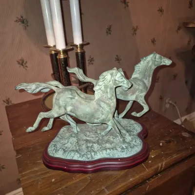 Sale Photo Thumbnail #19: Verdigris bronze-style sculpture depicting running horses mounted on a reddish-brown wooden base.