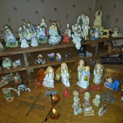 Sale Photo Thumbnail #307: Large collection of vintage figurine collectibles, featuring angels, animals, Christmas decor, and small resin and wooden knick-knacks arranged on a table and wooden shelving.