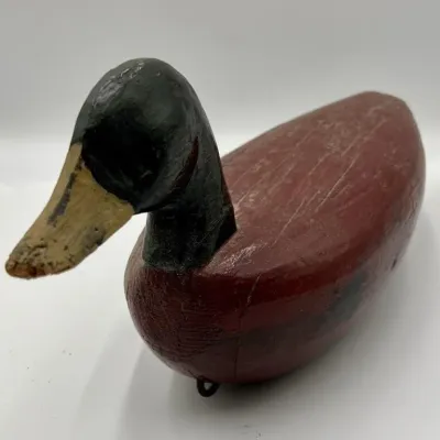Sale Photo Thumbnail #22: Vintage hand-carved wooden duck decoy with a painted red body, black head, and tan bill, showing rustic wear and age-related cracking.