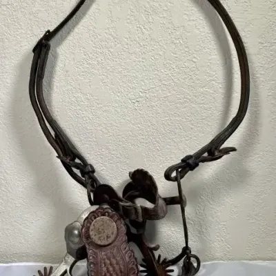 Sale Photo Thumbnail #24: Vintage leather horse bridle with bit and a pair of western spurs featuring tooled leather straps.