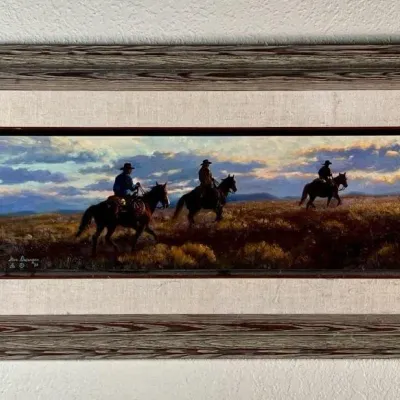 Sale Photo Thumbnail #4: Framed Western landscape painting depicting three cowboys on horseback, signed by the artist and dated 1983, presented in a rustic wood frame with a linen liner.
