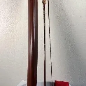Sale Photo Thumbnail #27: Vintage fly fishing rod with cork handle, accompanied by its brown hard carrying case featuring an eagle emblem and a red fabric storage sleeve.