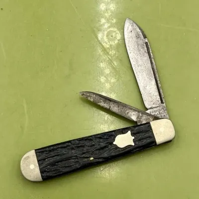 Sale Photo Thumbnail #21: Vintage Fairmount Cutlery Co. two-blade pocket knife with a textured black handle and a silver-tone shield inlay, showing age-appropriate wear and patina.