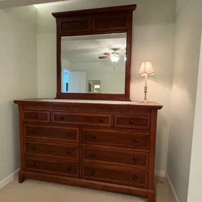 Traditional wooden nine-drawer dresser with attached matching mirror frame and dentil moulding trim.