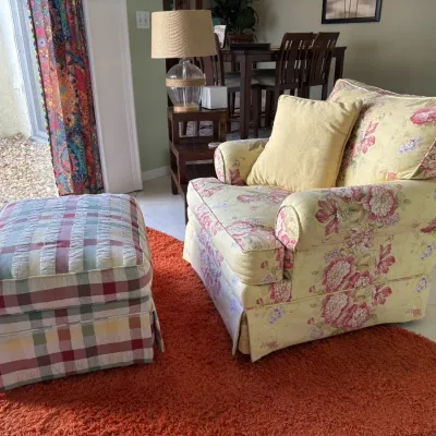 Yellow floral upholstered armchair with matching throw pillow and a coordinating plaid ottoman, arranged on an orange shag area rug.