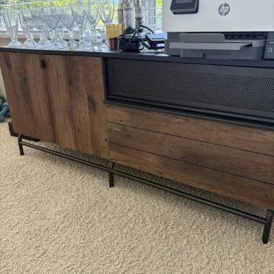 Modern industrial credenza featuring rustic wood-grain finishes and a black metal frame, displaying modern glassware and an HP printer.