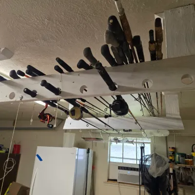 Sale Photo Thumbnail #2: Assorted fishing rods and reels stored in a ceiling-mounted wooden rack in a garage.