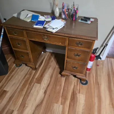 Sale Photo Thumbnail #6: Vintage wooden double-pedestal desk featuring brass batwing drawer pulls and bracket feet, showing some surface wear and scratches.