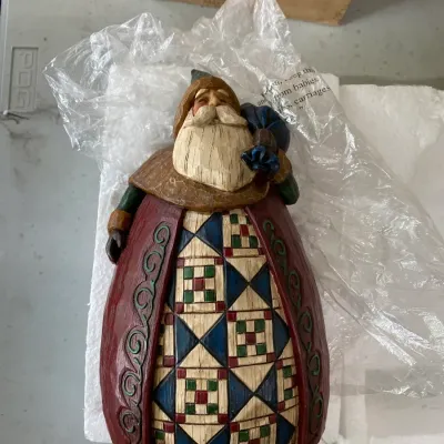 Jim Shore Heartwood Creek Santa figurine featuring a quilt-patterned robe, shown with its original packaging.