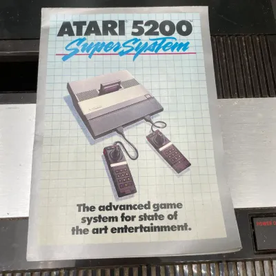 Vintage Atari 5200 SuperSystem owner's manual, showing some wear, resting on top of the console.