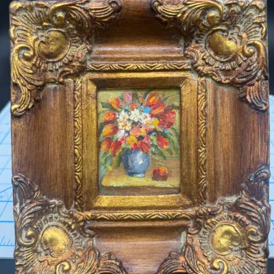 Miniature oil painting of a floral still life in a blue vase, housed in an ornate, heavily carved gilt and wood frame.