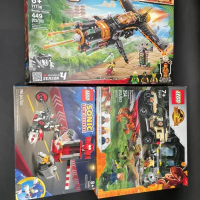 Three unopened LEGO sets in their original boxes, including Ninjago Legacy Boulder Blaster (71736), Sonic the Hedgehog Shadow's...