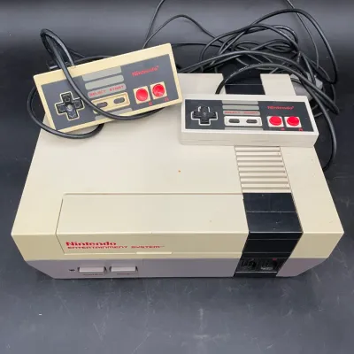 Vintage Nintendo Entertainment System (NES) console with two controllers, showing some age-related yellowing on the plastic casing.