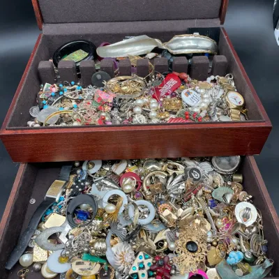 Two-tier wooden jewelry box filled with a large assortment of vintage costume jewelry, including necklaces, earrings, brooches, and watches.