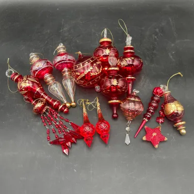 Collection of red and gold glass Christmas ornaments, featuring various shapes including finials, teardrops, and a beaded star.