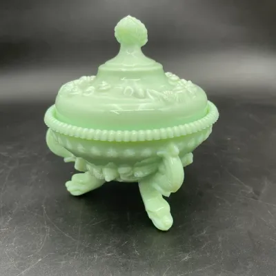 Vintage jadeite glass covered candy dish featuring a footed base, beaded rim, and ornate floral relief details.