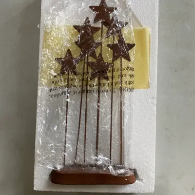 Rustic metal star tabletop decoration on a wooden base, packaged in its original styrofoam and plastic wrapping.