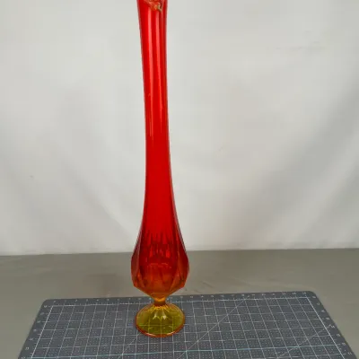 Mid-century modern Viking glass swung vase in a vibrant orange and red amberina colorway, featuring a pedestal base and a scalloped rim.