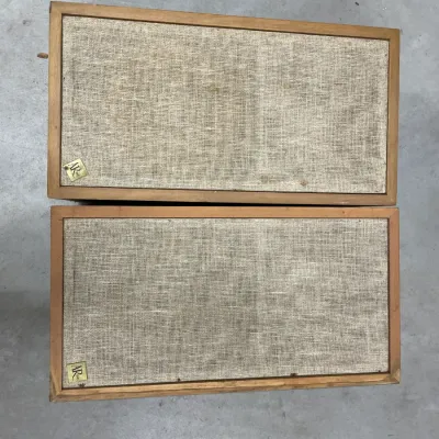Pair of vintage Acoustic Research (AR) speakers in wooden cabinets with woven linen grilles, showing some age-related wear.