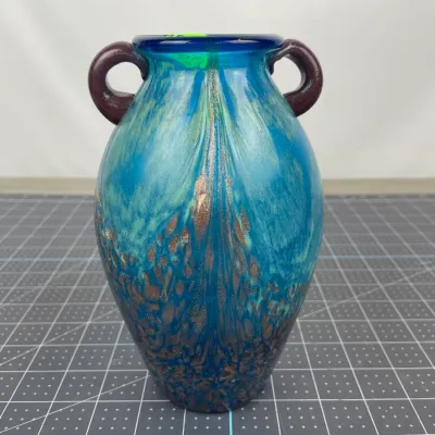 Art glass amphora vase featuring a vibrant turquoise and blue body with gold aventurine inclusions and dark purple applied handles.