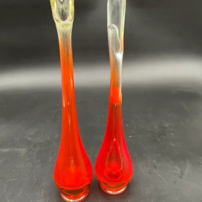 Pair of mid-century modern swung glass bud vases in a vibrant orange-red color with clear glass rims.