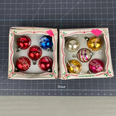Two vintage boxes of glass Christmas ornaments, featuring colorful stenciled and striped designs, presented in their original packaging.