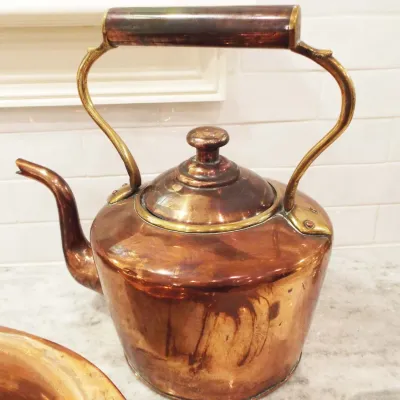 Vintage copper tea kettle with brass handle accents and a rich, aged patina.