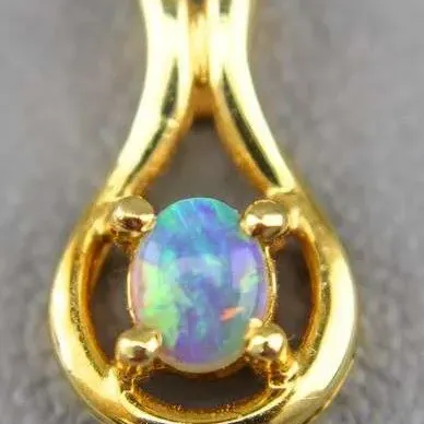 Vintage gold pendant featuring a prong-set oval opal with vibrant blue and green play-of-color, suspended within a teardrop-shaped frame.