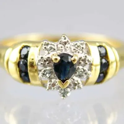 Vintage 14k yellow gold ring featuring a pear-cut blue sapphire surrounded by a diamond halo, flanked by channel-set sapphire accents.
