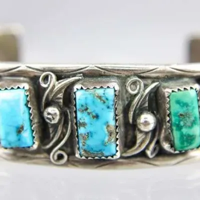 Vintage Native American sterling silver cuff bracelet featuring five rectangular turquoise stones in serrated bezel settings, accented...