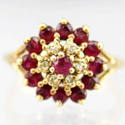 Vintage gold cluster ring featuring a central ruby surrounded by a halo of small diamonds and an outer halo of round-cut rubies in prong...