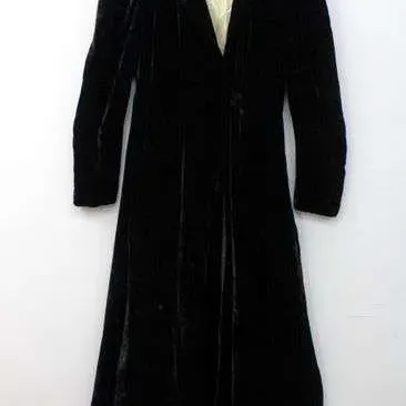 Vintage black velvet full-length coat featuring a cream-colored lining and collar trim, displayed on a wooden hanger.