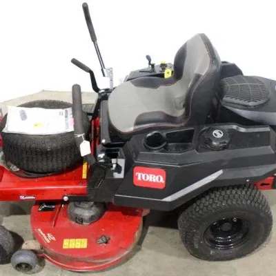 Toro TimeCutter zero-turn riding lawn mower with a 42-inch deck, featuring a Kohler engine, high-back seat, and an extra tire resting on...