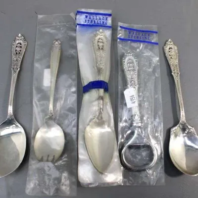 Five pieces of Wallace sterling silver flatware, including serving spoons and a bottle opener, with three items still in their original...