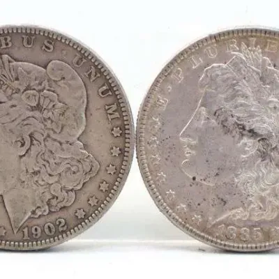 Two United States Morgan silver dollars, dated 1902 and 1885, showing moderate wear and natural patina.