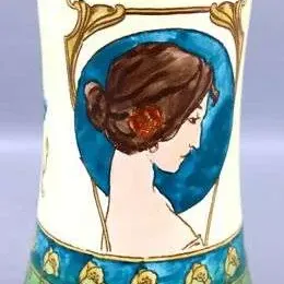 Art Nouveau ceramic vase featuring a hand-painted portrait of a woman in profile, framed by organic gold flourishes and a green floral base.