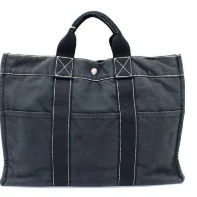 Hermès Fourre-Tout canvas tote bag in dark grey with white contrast stitching and snap closure.