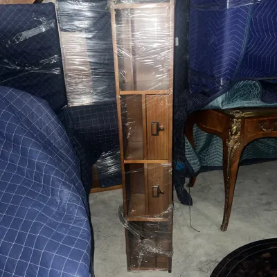 Sale Photo Thumbnail #84: Mid-century modern style tall, narrow wooden media storage tower wrapped in plastic, featuring open shelves and small drawers with dark metal pulls.