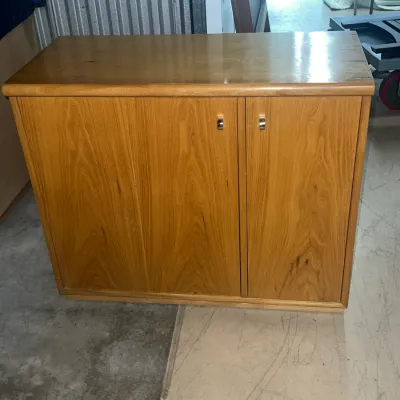 Sale Photo Thumbnail #49: Mid-century modern style wooden storage cabinet with a light oak finish, featuring two doors with small metal pulls.