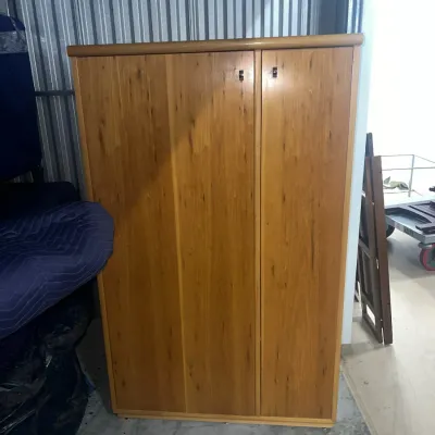 Sale Photo Thumbnail #55: Contemporary light wood wardrobe cabinet with two doors and small metal pulls, suitable for storage or clothing.