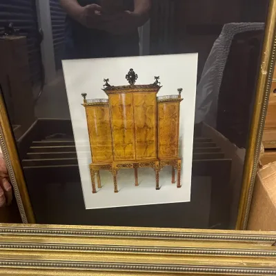 Sale Photo Thumbnail #14: Framed art print depicting an ornate, antique-style wooden cabinet, housed in a beaded gold-finished frame with a dark mat.