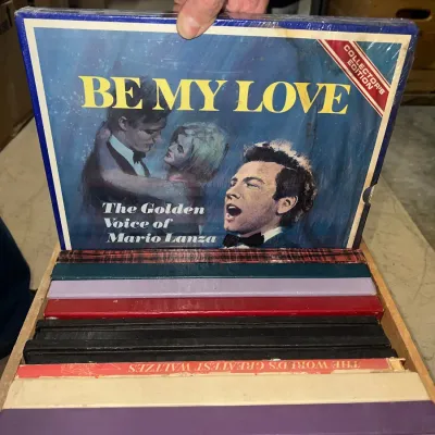 Sale Photo Thumbnail #7: "Be My Love: The Golden Voice of Mario Lanza" collector's edition vinyl box set, shown in a wooden storage rack with other vintage record albums.