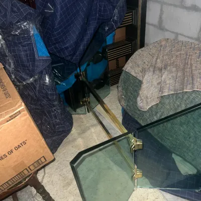 Sale Photo Thumbnail #61: Three-panel glass fireplace screen with brass hinges, shown stored alongside moving blankets and boxes.