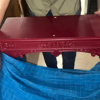 Sale Photo Thumbnail #88: Ornate wooden console table painted in a deep burgundy red, featuring intricate scrollwork and floral carvings along the apron and legs.