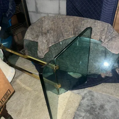 Sale Photo Thumbnail #42: Disassembled mid-century modern style dining table featuring a thick glass top and a brass-plated metal base with glass support panels.