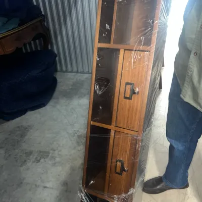 Sale Photo Thumbnail #87: Mid-century modern style wooden shelving unit with drawers, wrapped in protective plastic for transport.