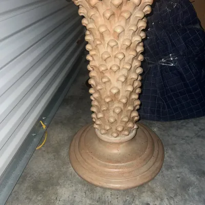 Sale Photo Thumbnail #47: Terracotta-colored pedestal stand featuring a heavily textured, stylized leaf or pinecone pattern on the column and a tiered circular base.