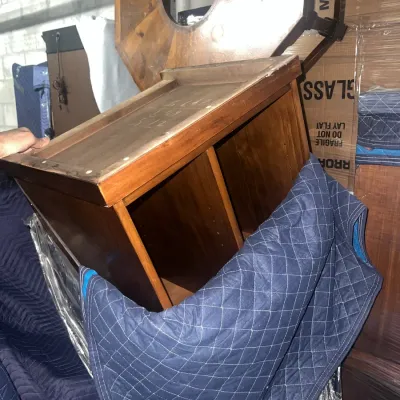 Sale Photo Thumbnail #79: Mid-century wooden nightstand or side table with open shelving, shown wrapped in a blue moving blanket for transport.