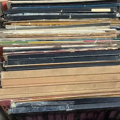 Sale Photo Thumbnail #71: A wooden crate filled with vintage vinyl records and box sets, showing worn spines and sleeves from various eras.