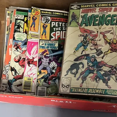 Sale Photo Thumbnail #72: A collection of vintage Marvel comic books from the late 1970s, including Marvel Super Action starring The Avengers and Peter Parker, The Spectacular Spider-Man, stored in a cardboard box.